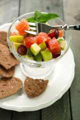 Fruit salad in glass bowl, on wooden background