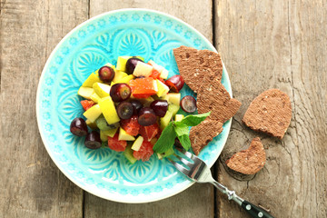 Fruit salad on plate, on wooden background