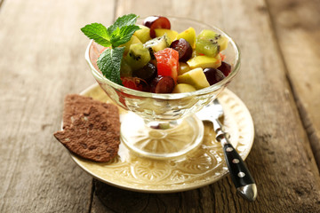 Fruit salad in glass bowl, on wooden background
