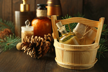 Essential oil of pine, handmade soap in wooden bucket and spa treatments on wooden background