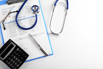 Stethoscope with medical history and calculator isolated on white