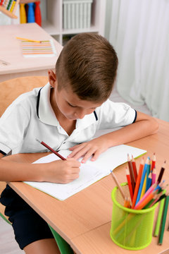 Little boy drawing at the desk in classroom