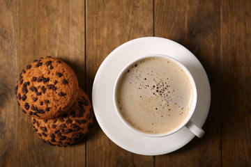 Cup of coffee with cookies on wooden table, top view