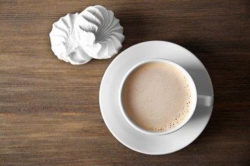 Cup of coffee with zephyr and beans on wooden table, top view