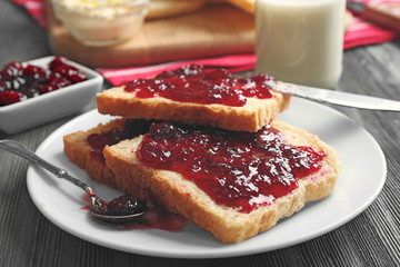 Bread with butter and homemade jam in plate on wooden table, closeup