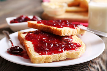 Bread with butter and homemade jam in plate on wooden table, closeup