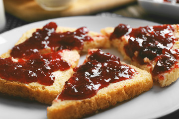 Bread with butter and homemade jam in white plate, closeup