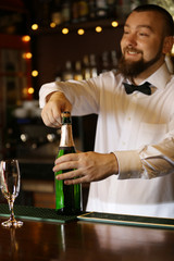Portrait of handsome bartender with champagne bottle