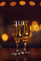 Two glasses of champagne, on bar counter, on blurred lights background