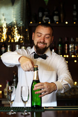 Portrait of handsome bartender with champagne bottle