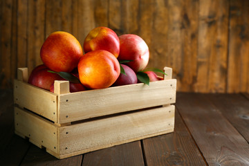 Fresh peaches in crate on wooden background