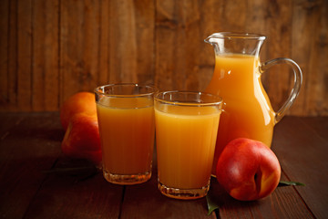 Peach juice and ripe peaches on wooden background