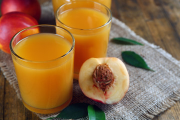 Ripe peaches and glass of juice on wooden background