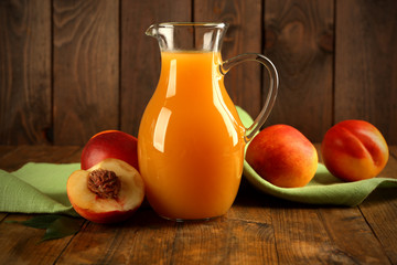 Peach juice and ripe peaches on wooden background