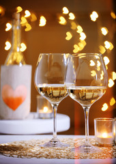 Wine glass near bottle on hearts bokeh background