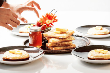 Toasted crumpets with honey drizzled over them and strawberries in the background.
