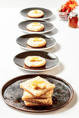 Toasted crumpets with honey drizzled over them and strawberries in the background.