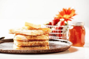 Toasted crumpets with honey drizzled over them and strawberries in the background.