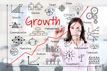 Young business woman writing growth graph. Office background. 