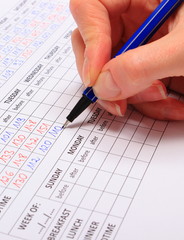 Hand of woman writing data to medical form