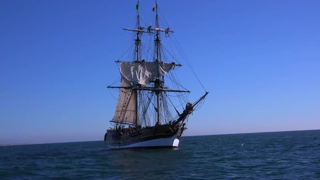 A tall masted clipper ship sails on the high seas.
