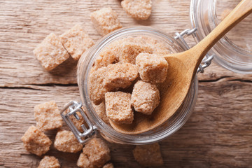 Pieces of lump cane sugar in a glass jar close up. horizontal top view 
