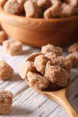 lump cane sugar macro in a wooden spoon on the table. Vertical
