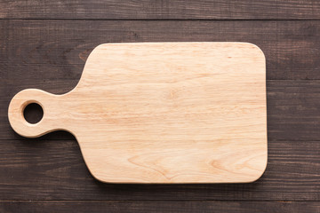 Cutting board on the wooden background. Top view