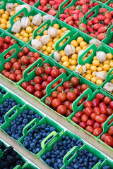 series of baskets of berries,tomatoes and physalis at market