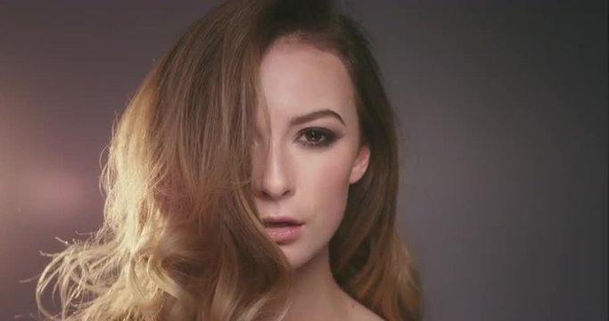 Sexy woman fashion spinning around hair in slow motion on dark background with moody lighting
