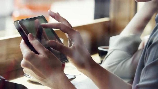 Closeup woman hands using ipad touchscreen tablet display in cafe