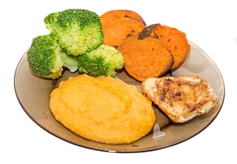 Transparent plate with fresh green broccoli, smashed sweet potatoes and slice of orange sweet potatoes, chiken meat.