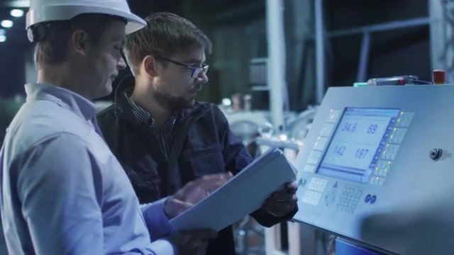 Engineer and Factory Worker are Setting Up CNC Lathe Machine Together. 
Shot on RED Cinema Camera in 4K (UHD). Its easy scale, rotate and crop without loosing quality.