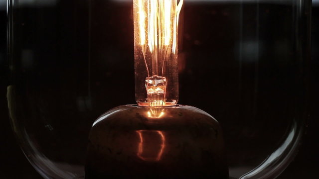 A bright orange glow illuminates from a glass bulb, close up