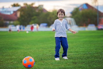 Fototapeta premium Little toddler boy playing soccer and football, having fun outdo