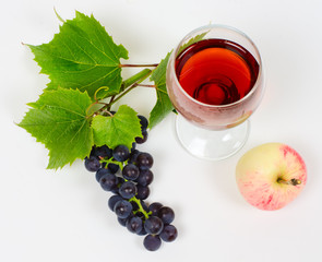 the cluster of grapes and apple lie near a wine glass with brand