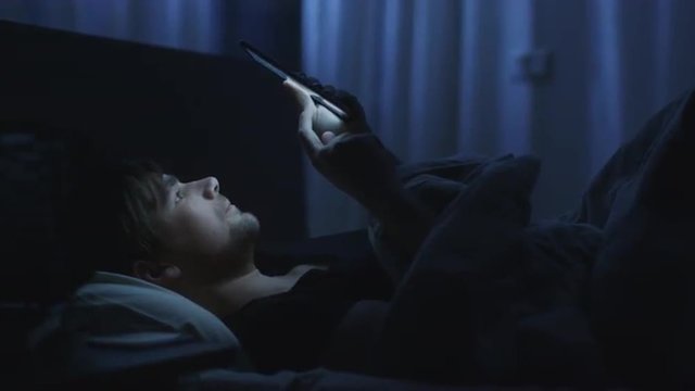 Man is Using Tablet in Bed at Home at Night Time.