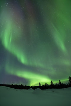 Aurora borealis over snowy winter landscape, Finnish Lapland