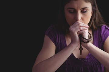Woman praying with wooden rosary beads  - obrazy, fototapety, plakaty