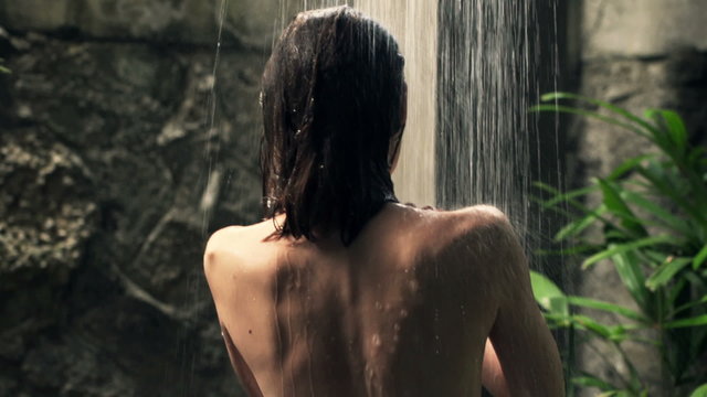 Woman washing her back under shower in open bathroom