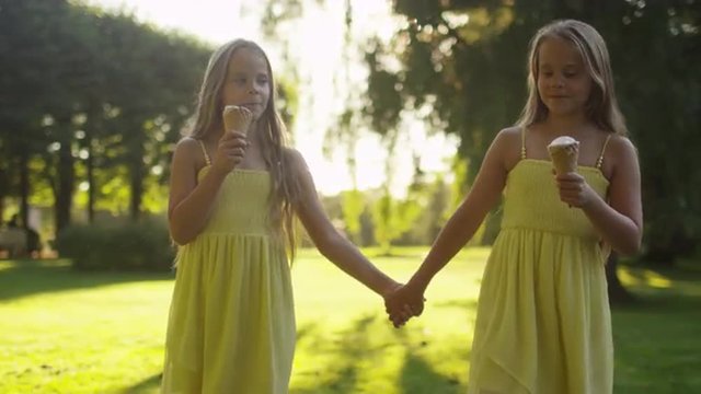 Two Girls are Walking at Park and Holding Ice Cream in Hands