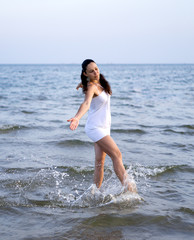 Fototapeta na wymiar Happy brunette girl dancing over the sea