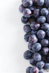 Fresh plums on white wooden background