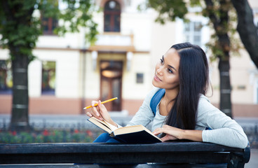 Female student sitting on the bench with book