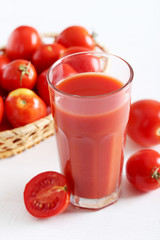 Fresh red tomatoes and tomato juice in glass on wooden table