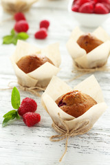 Fresh cupcakes with raspberries on white wooden background