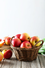 Red apples in basket on grey wooden background