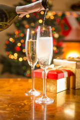 two champagne glasses on table being filled from bottle