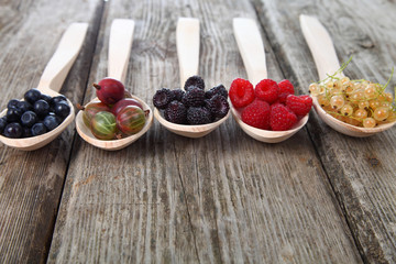 Different ripe berries in a wooden spoons