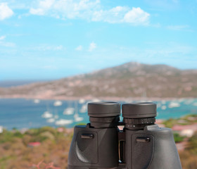 White paid telescope stands on sea coast over blue sky background